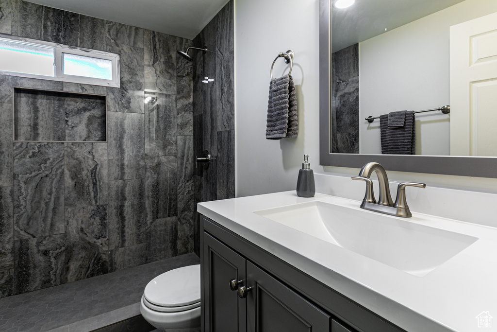 Bathroom with a tile shower, vanity, and toilet