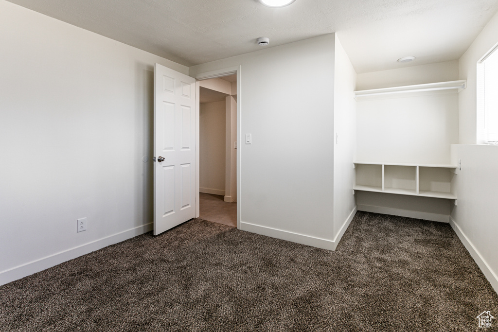 Unfurnished bedroom featuring dark colored carpet and a closet