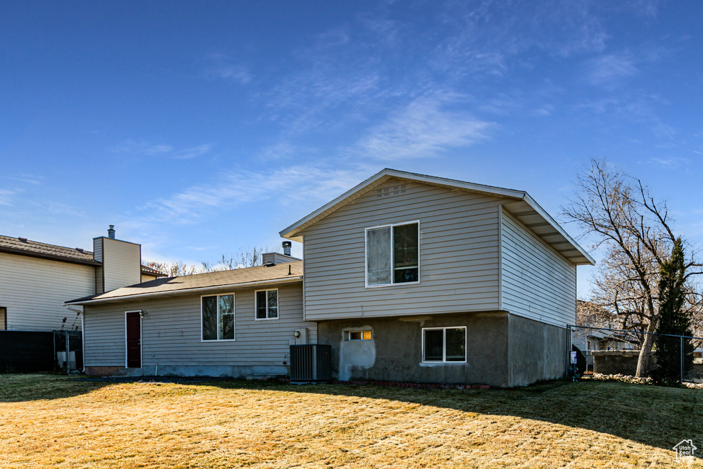 Back of house featuring central air condition unit and a yard