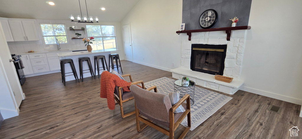 Living room featuring lofted ceiling, sink, a fireplace, and dark hardwood / wood-style flooring