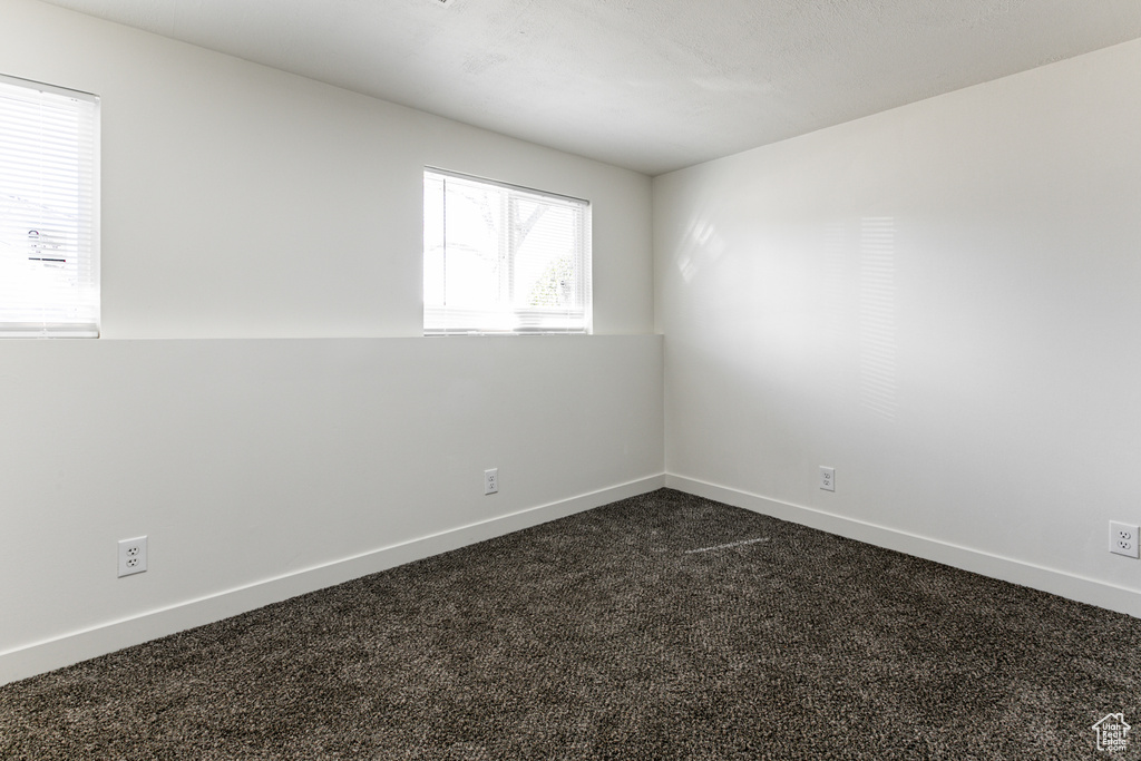 Unfurnished room featuring dark colored carpet