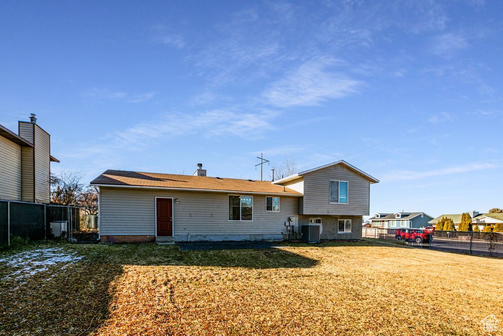 Rear view of property featuring cooling unit and a yard