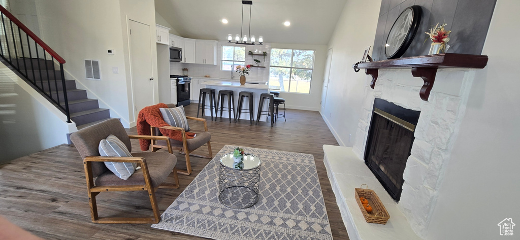 Living room with dark wood-type flooring, lofted ceiling, and a chandelier