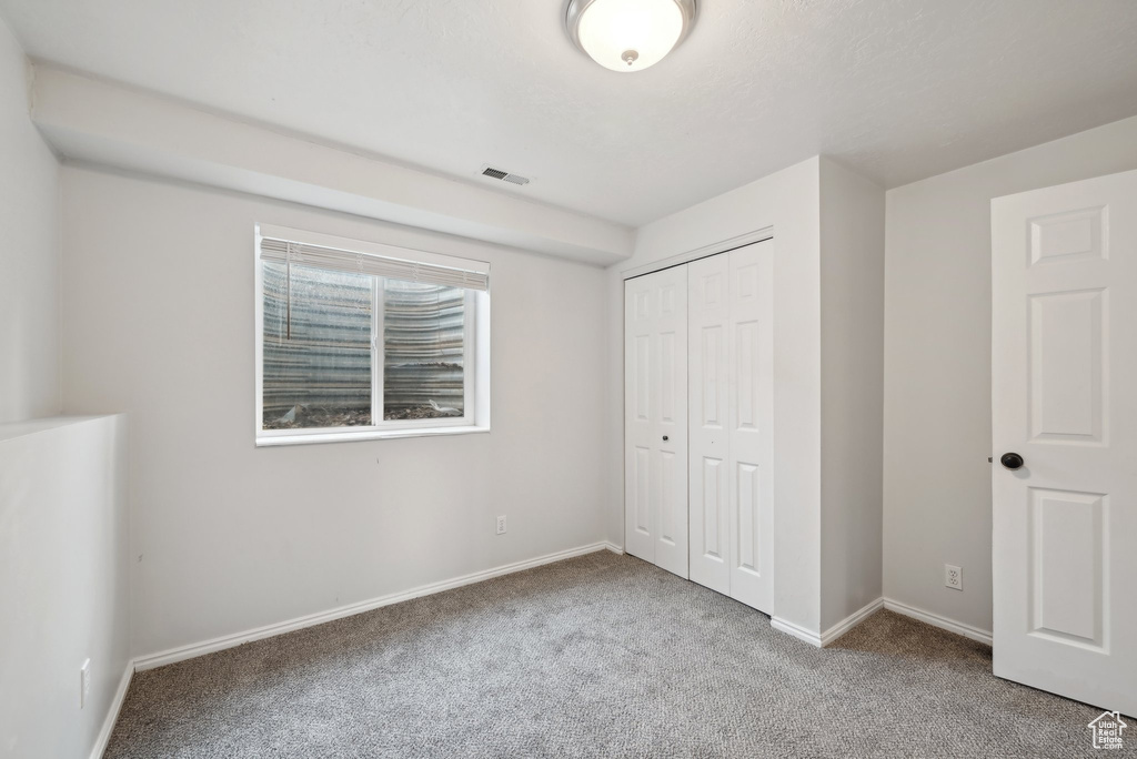 Unfurnished bedroom with carpet floors, a closet, visible vents, and baseboards