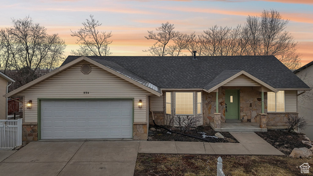 View of front of home with a garage, stone siding, a shingled roof, and concrete driveway