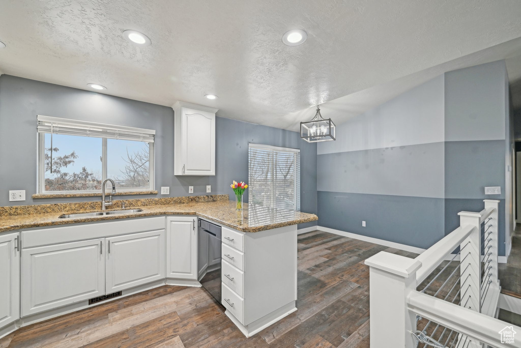 Kitchen with visible vents, dishwashing machine, a peninsula, white cabinetry, and a sink