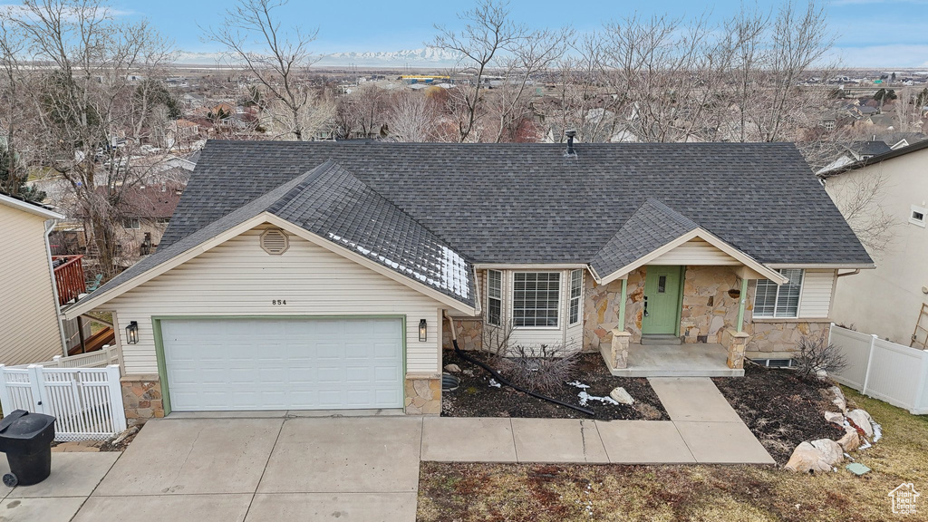 View of front of property with a shingled roof, stone siding, and fence