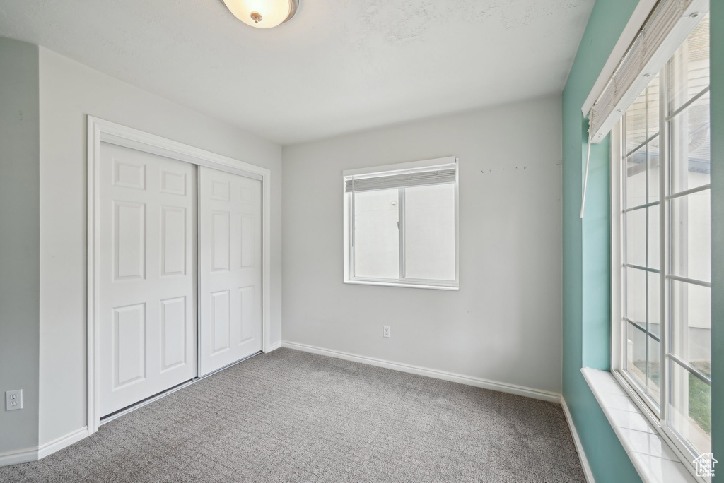 Unfurnished bedroom with carpet, a closet, and baseboards