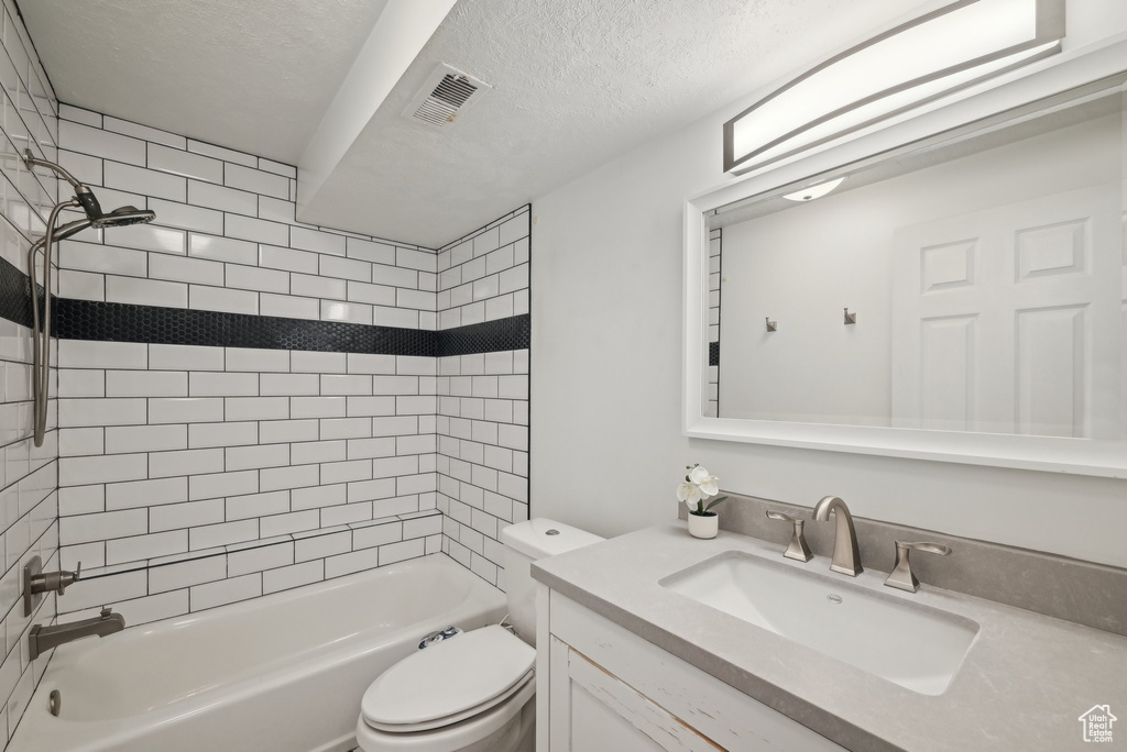 Bathroom with shower / bathtub combination, visible vents, toilet, vanity, and a textured ceiling