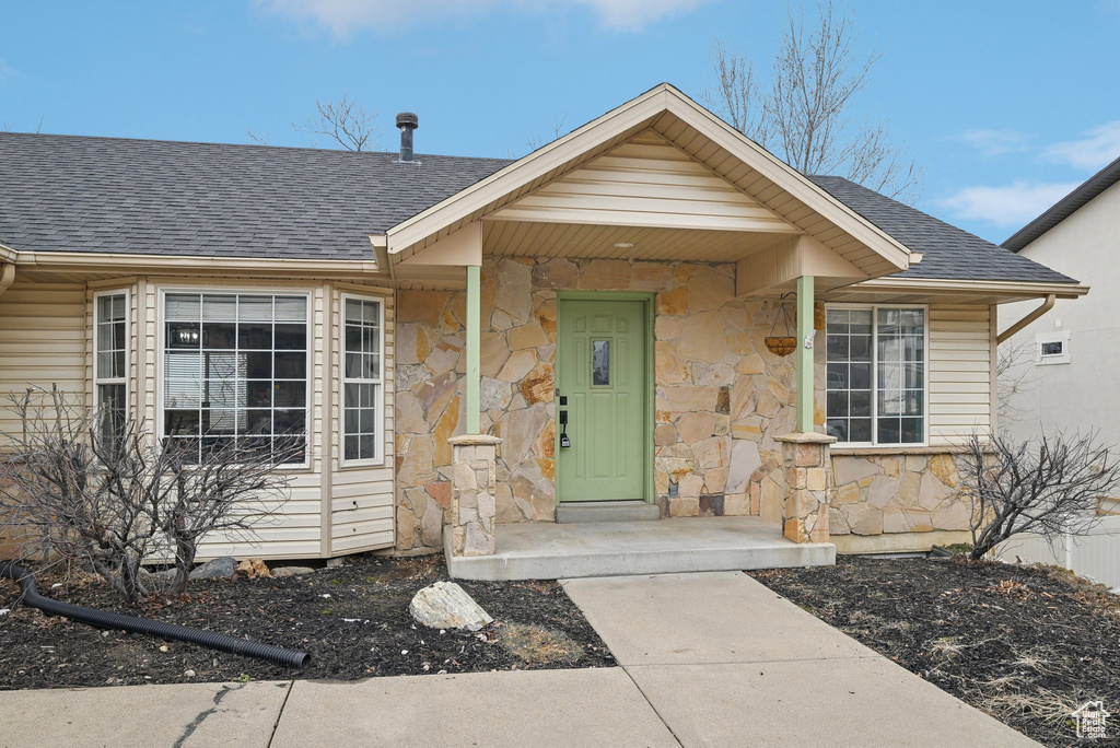 View of front of property featuring a shingled roof and stone siding