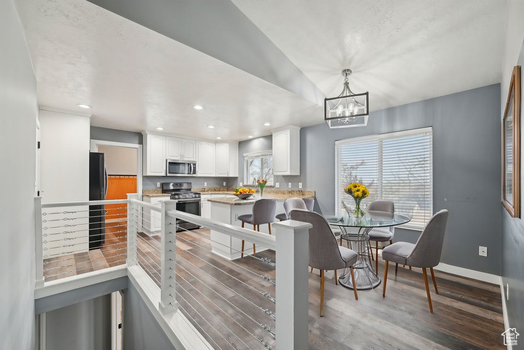 Dining space featuring light wood-style floors, baseboards, a notable chandelier, and recessed lighting