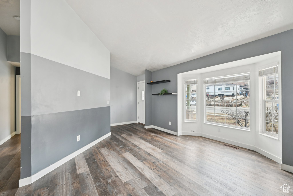 Spare room with wood finished floors, visible vents, and baseboards