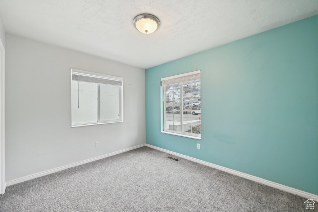 Carpeted empty room with visible vents and baseboards