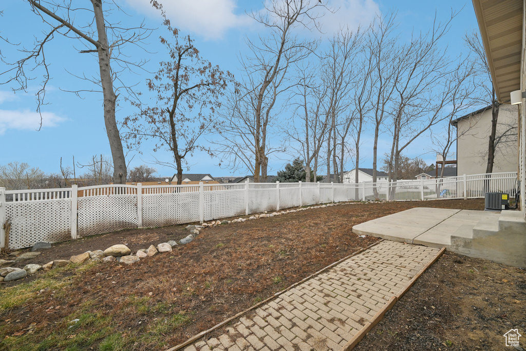 View of yard with central air condition unit, a fenced backyard, and a patio