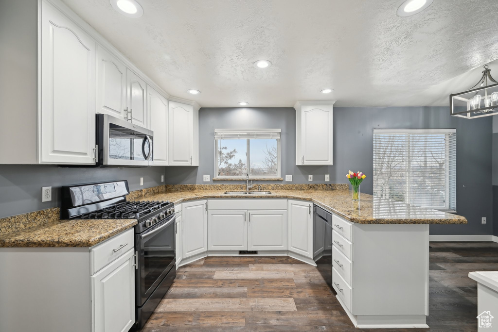 Kitchen with dishwasher, gas range, stainless steel microwave, a peninsula, and a sink