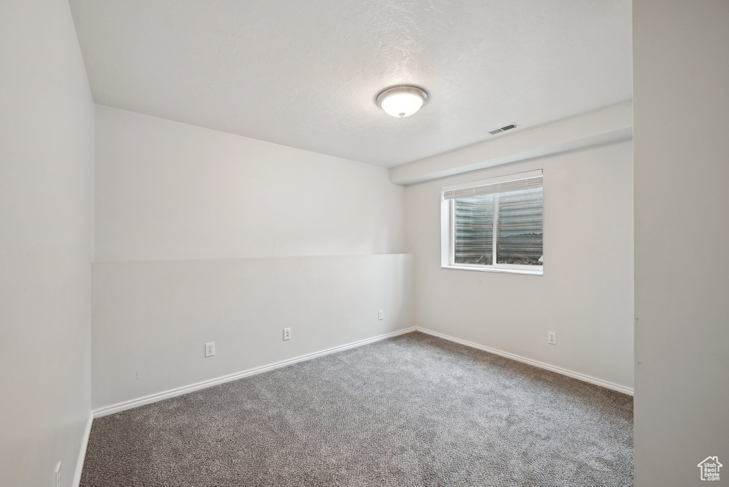 Carpeted empty room featuring visible vents, baseboards, and a textured ceiling