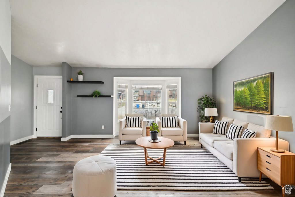 Living area featuring vaulted ceiling, dark wood-style flooring, and baseboards