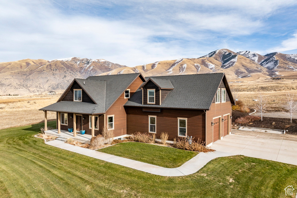 View of front of home featuring covered porch, a mountain view, driveway, a garage, and a front lawn