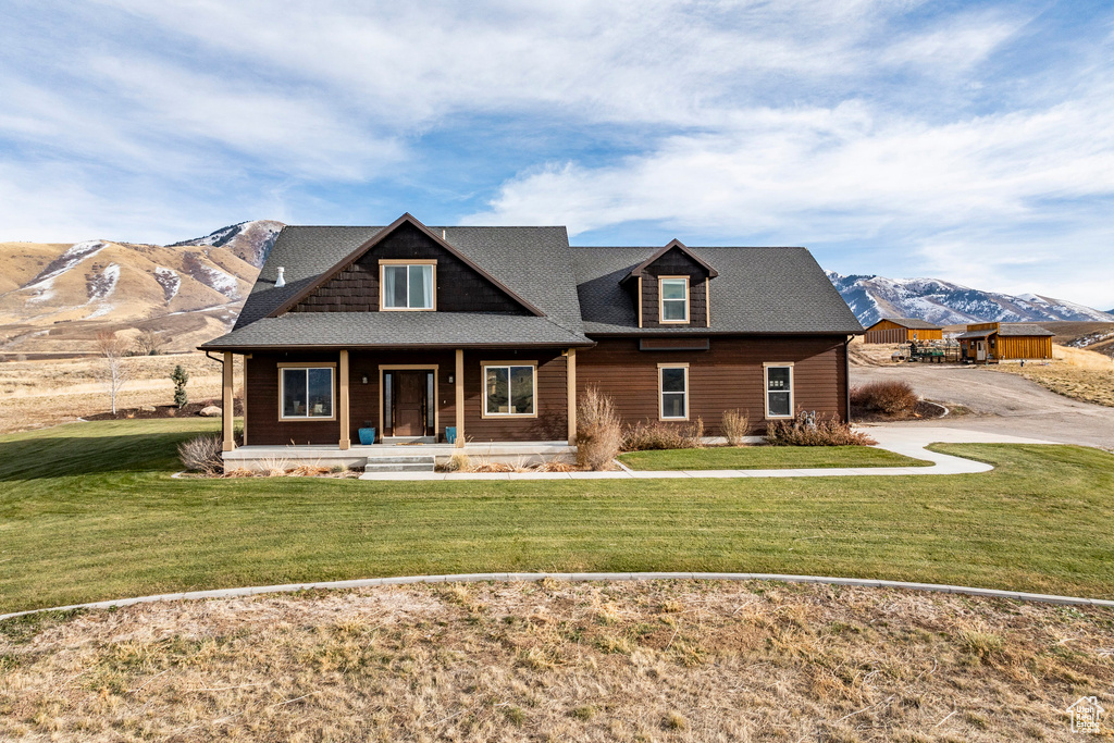 View of front of property with a porch, a mountain view, and a front yard