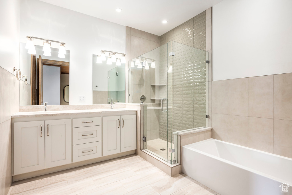Full bath with a stall shower, double vanity, a bath, and recessed lighting