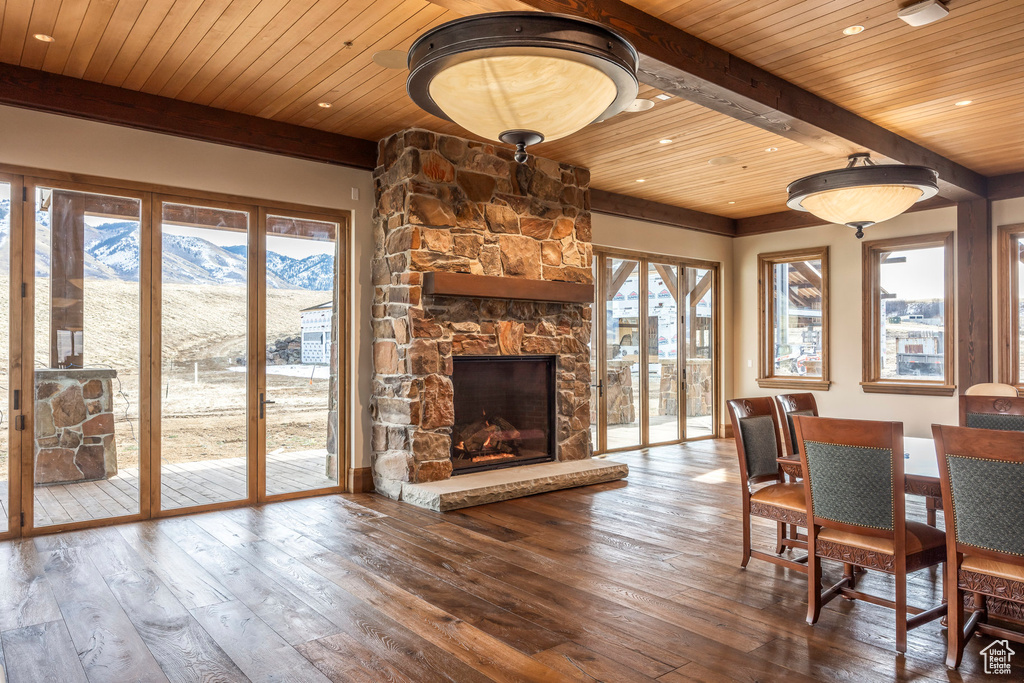 Dining room with a wood ceiling with exposed beams, a mountain view, hardwood / wood-style floors, recessed lighting, and a stone fireplace