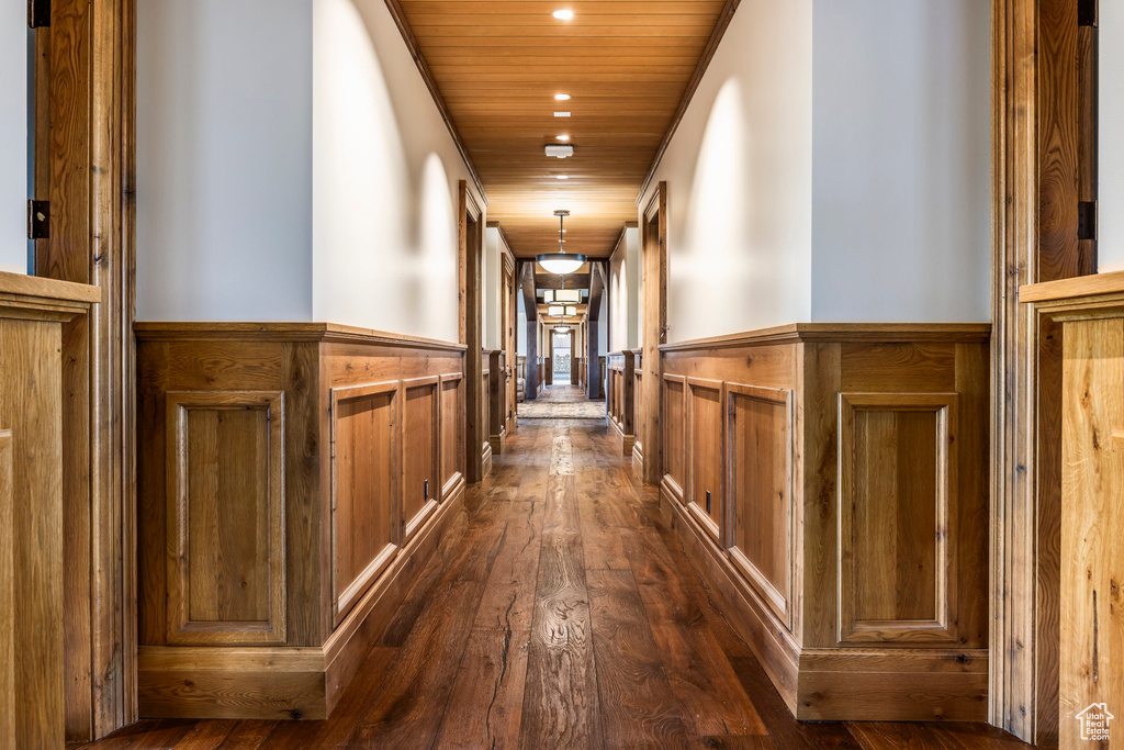 Corridor with a wainscoted wall, recessed lighting, wood ceiling, and dark wood finished floors