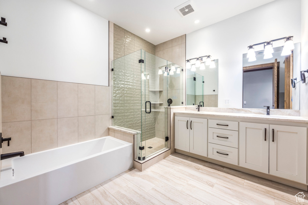 Bathroom featuring a garden tub, double vanity, a shower stall, and recessed lighting