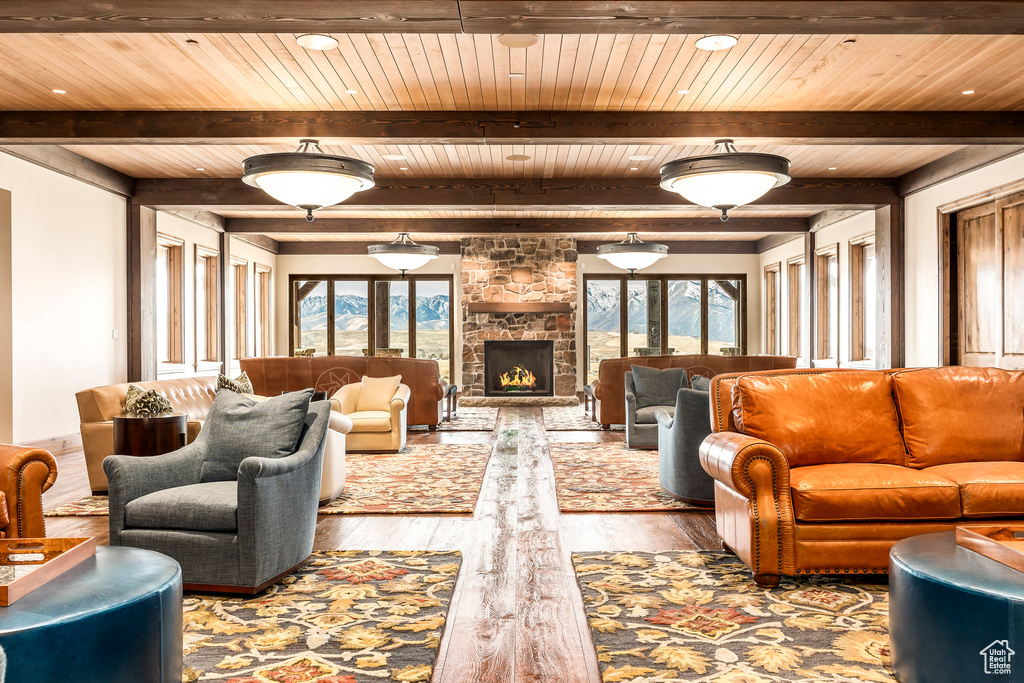 Living room with healthy amount of natural light, wood finished floors, a fireplace, and a wood ceiling with exposed beams