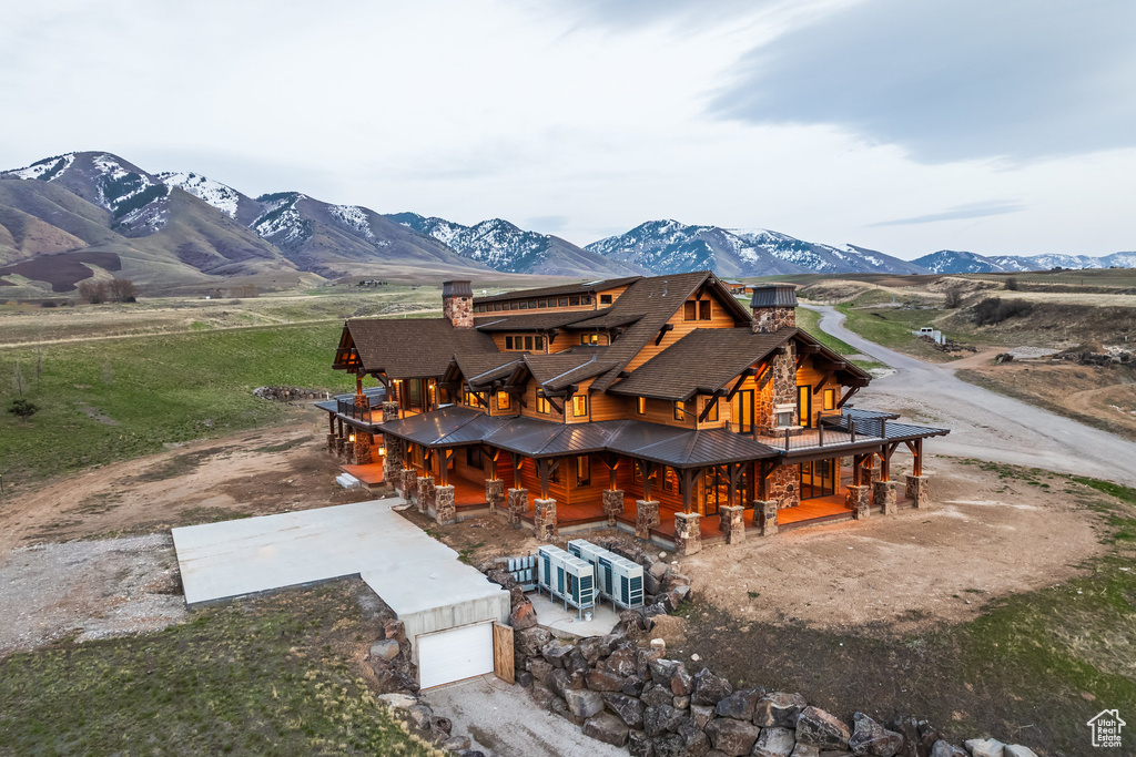 Back of property with a chimney, an attached garage, a mountain view, dirt driveway, and a standing seam roof