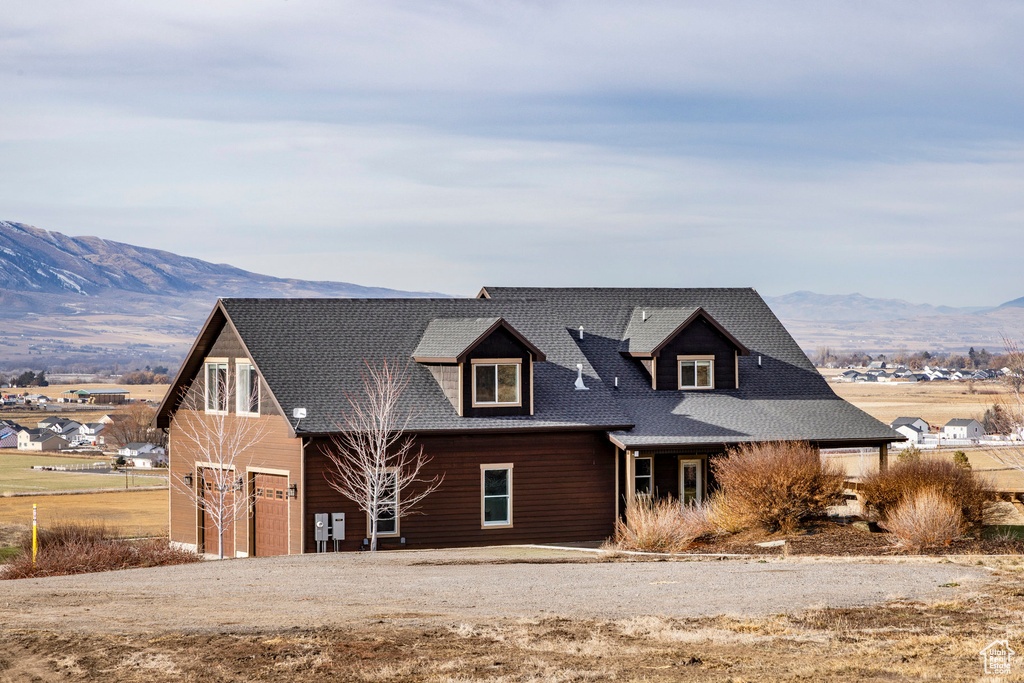 View of front of house featuring a mountain view, driveway, a garage, and roof with shingles