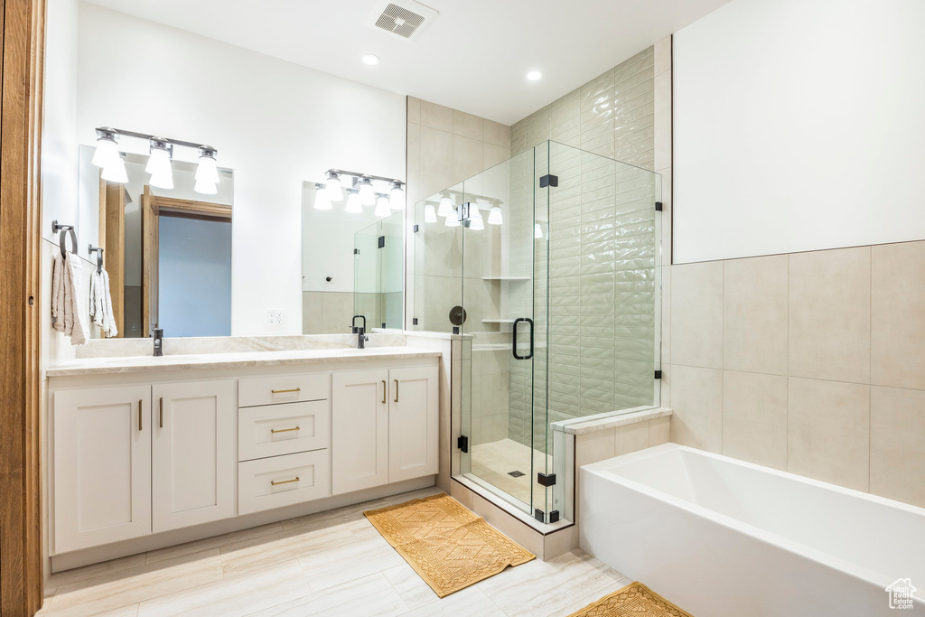 Full bathroom with a stall shower, double vanity, a garden tub, and recessed lighting