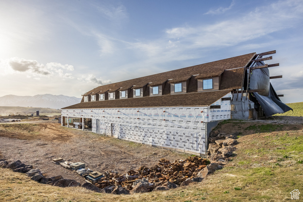 View of property exterior featuring a gambrel roof, a mountain view, and roof with shingles
