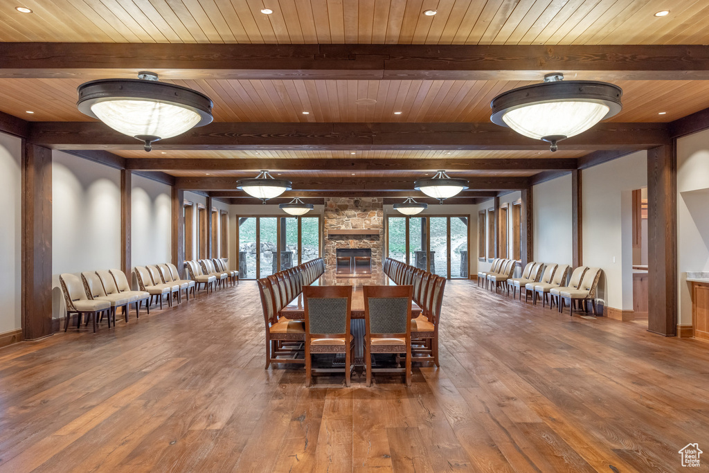 Dining space featuring wood-type flooring, a wooden ceiling with exposed beams, recessed lighting, and a fireplace