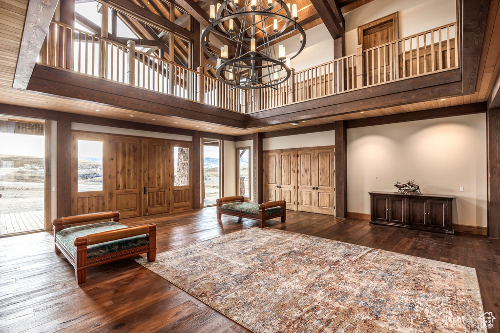 Entrance foyer with a high ceiling, hardwood / wood-style floors, a chandelier, and beam ceiling