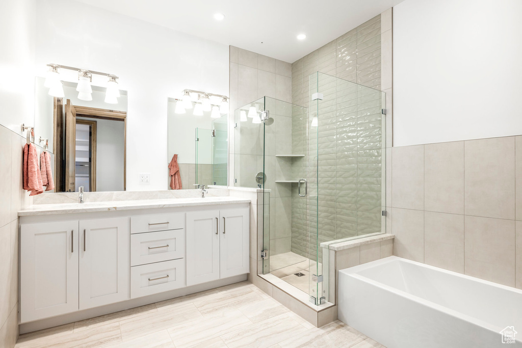 Full bathroom with a stall shower, double vanity, a bath, and recessed lighting