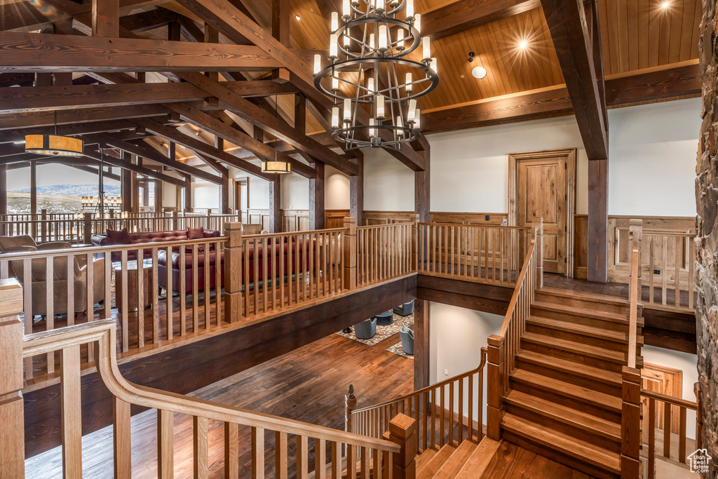 Stairway with hardwood / wood-style floors, a chandelier, a wainscoted wall, and wood ceiling