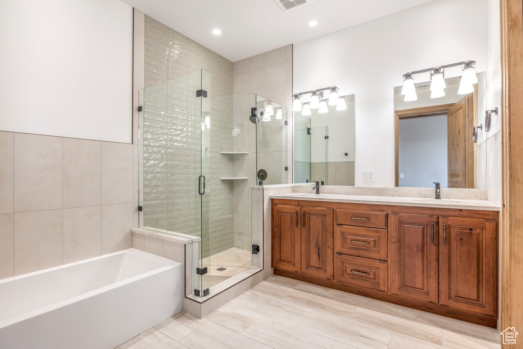Full bath with a shower stall, a garden tub, double vanity, and recessed lighting