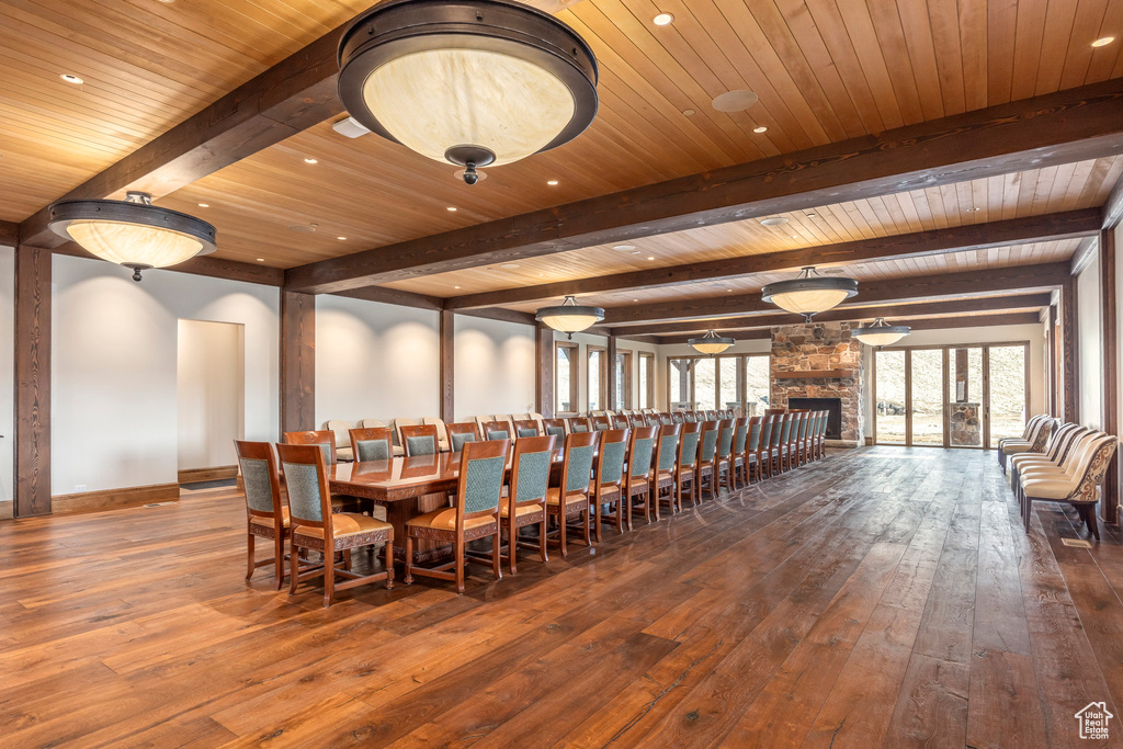 Dining space with dark wood-style flooring, a wood ceiling with exposed beams, a fireplace, and recessed lighting