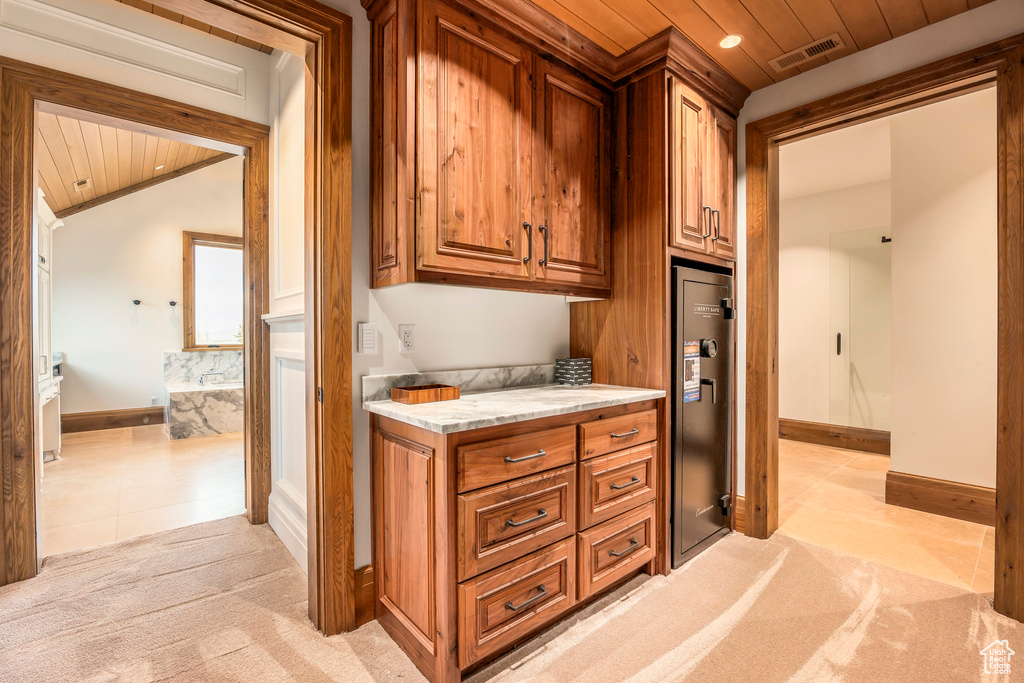 Kitchen featuring wood ceiling, brown cabinets, light carpet, light tile patterned floors, and vaulted ceiling