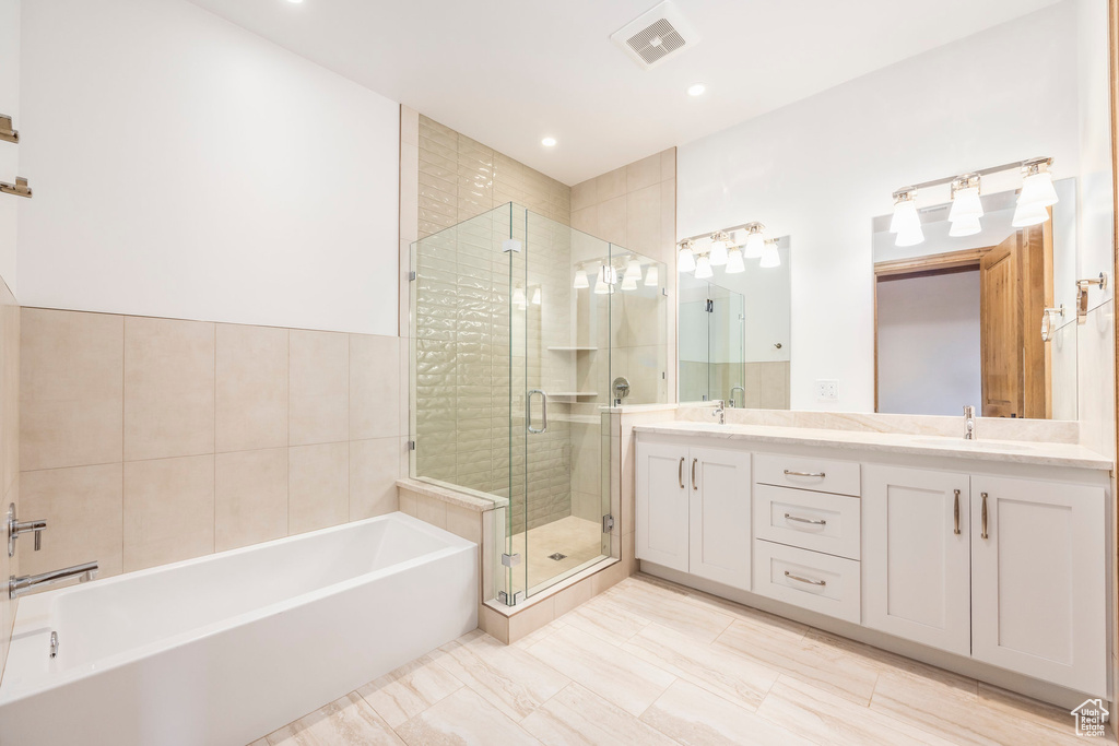 Bathroom with a garden tub, double vanity, a shower stall, and recessed lighting
