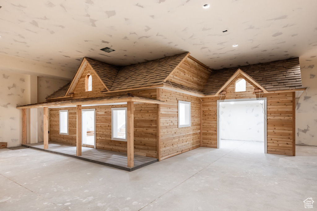 Bonus room featuring a towering ceiling and wooden walls