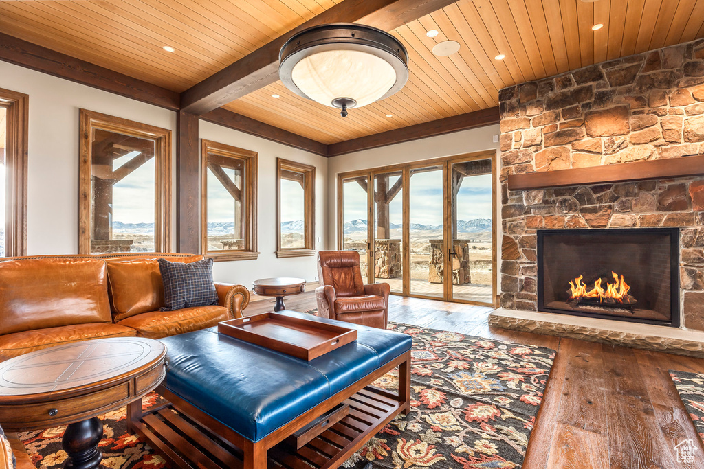 Living area with a wood ceiling with exposed beams, a mountain view, healthy amount of natural light, hardwood / wood-style floors, and recessed lighting