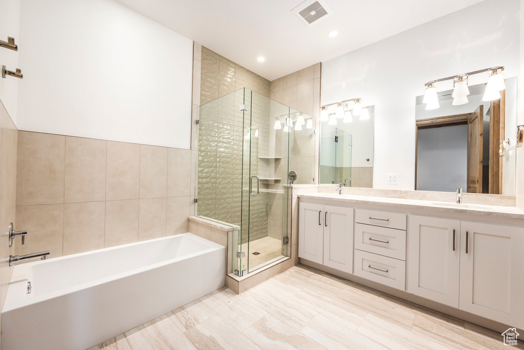 Bathroom featuring a garden tub, double vanity, a stall shower, and recessed lighting