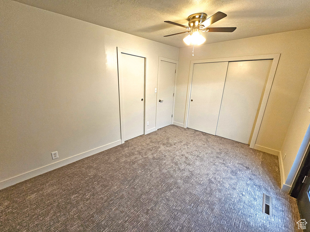 Unfurnished bedroom with ceiling fan, carpet, and a textured ceiling