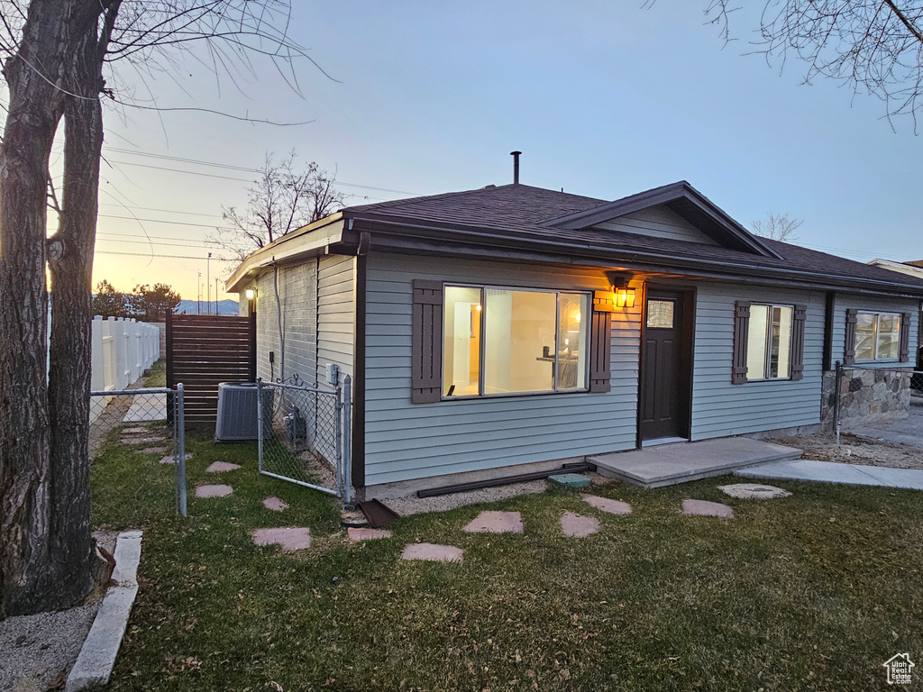 View of front of property with central AC unit and a lawn