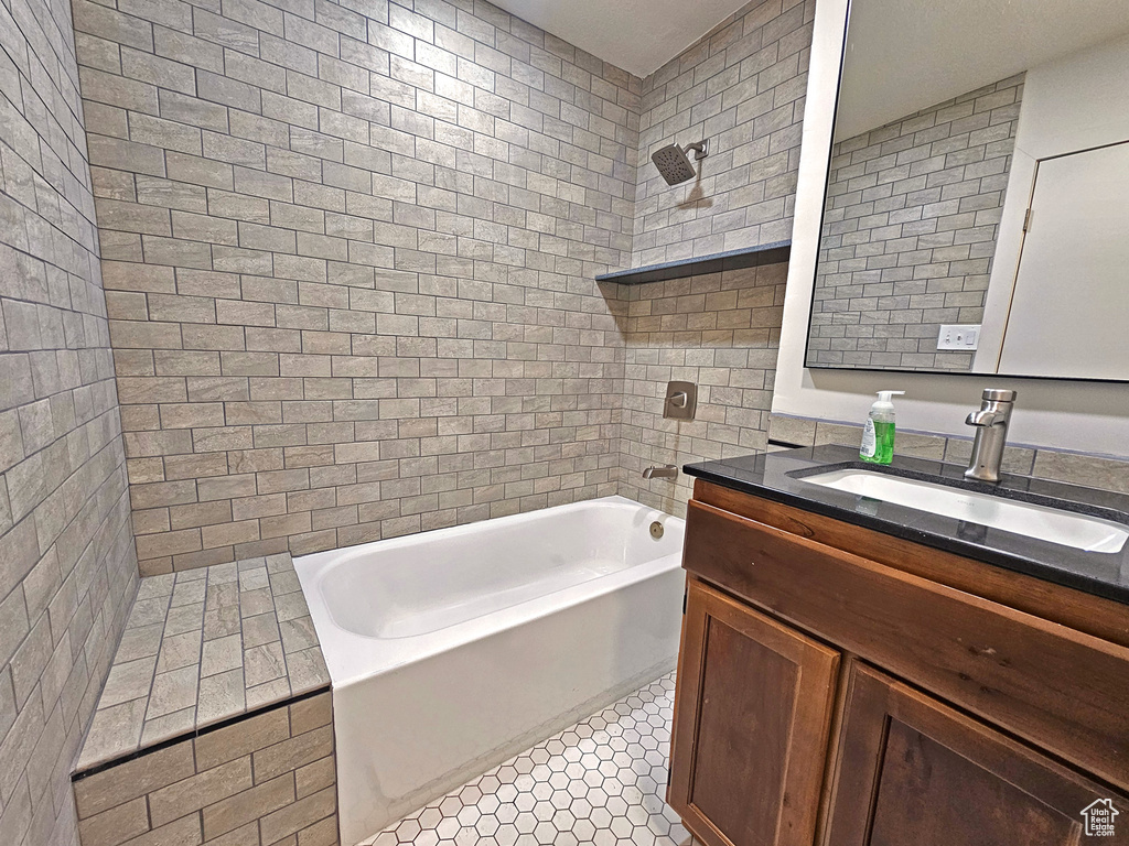 Bathroom with vanity, tile patterned floors, and tiled shower / bath