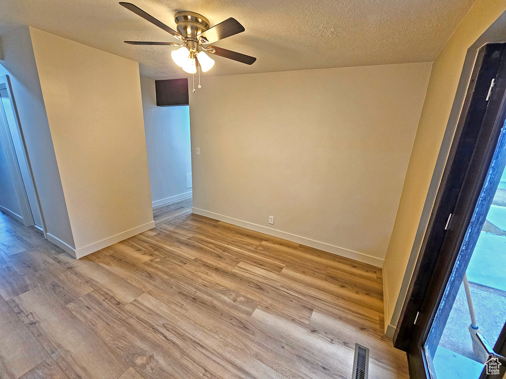 Spare room with ceiling fan, a healthy amount of sunlight, light hardwood / wood-style flooring, and a textured ceiling