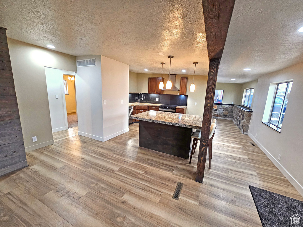 Kitchen featuring pendant lighting, a kitchen island, sink, and a textured ceiling