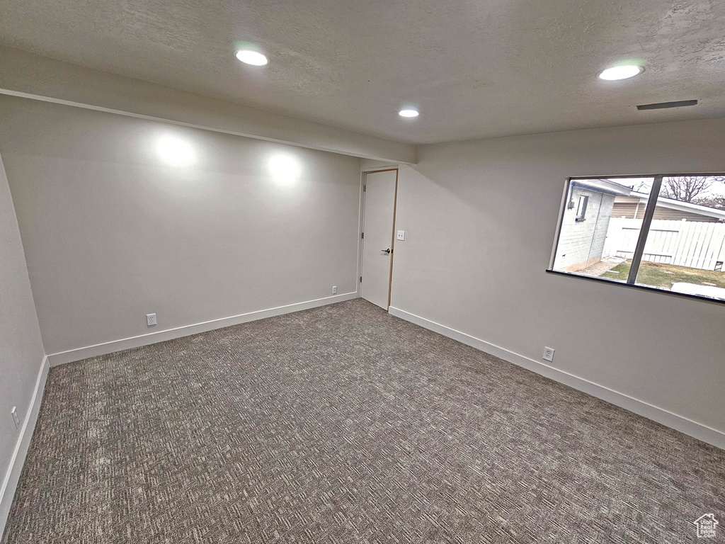 Spare room with dark colored carpet and a textured ceiling