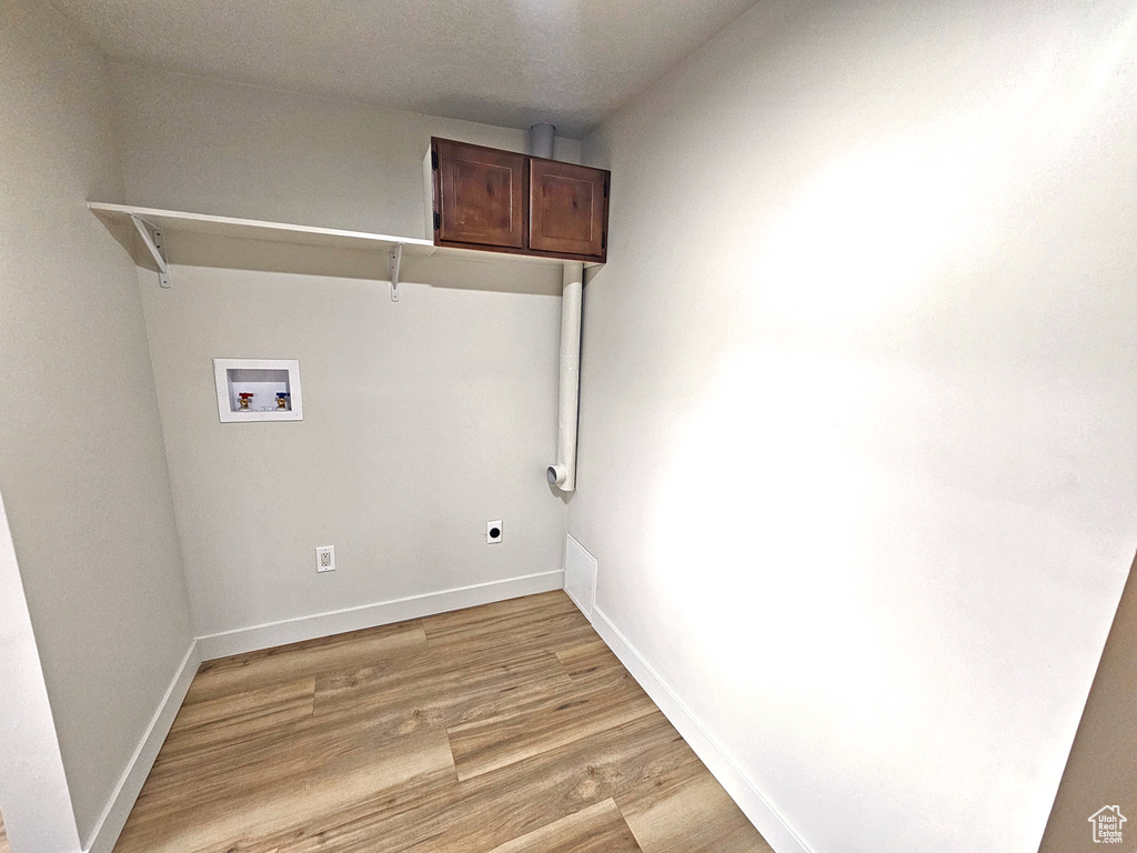 Clothes washing area featuring cabinets, washer hookup, hookup for an electric dryer, and light hardwood / wood-style flooring